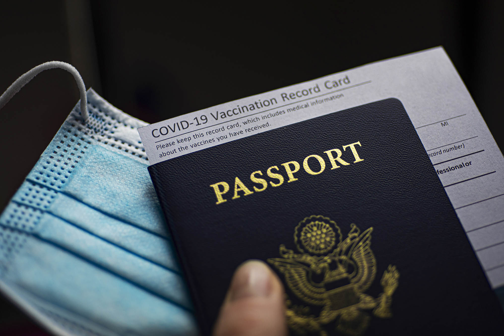 COVID-19 Vaccination Record card, Passport of USA and Medical Mask. Immune passport or certificate for travel concept.
